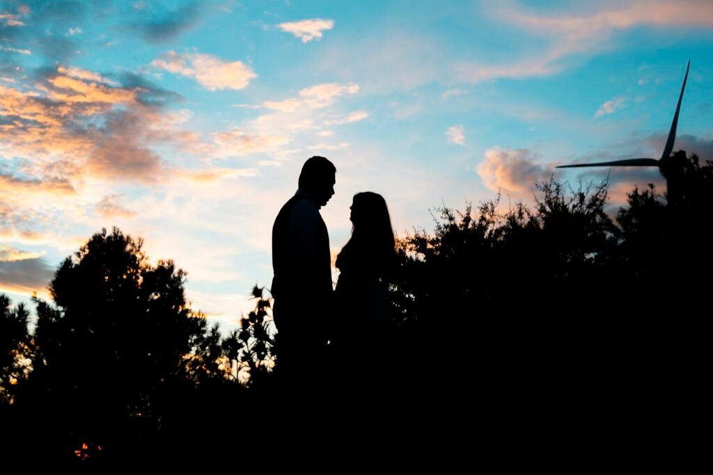 a man and a woman standing in front of a sunset